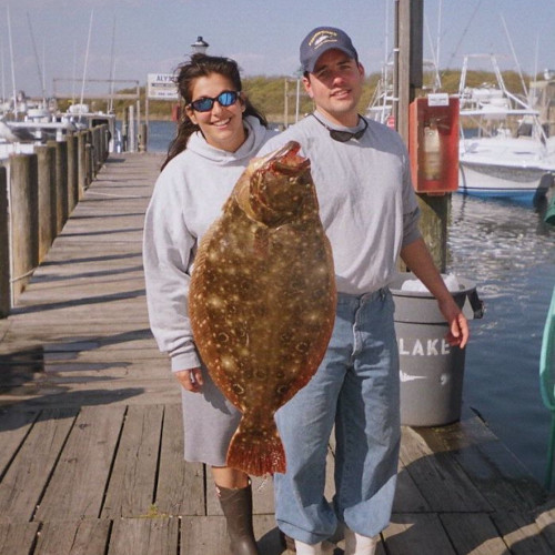 Captains Jill and Steve holding up a very large fluke on the marina.